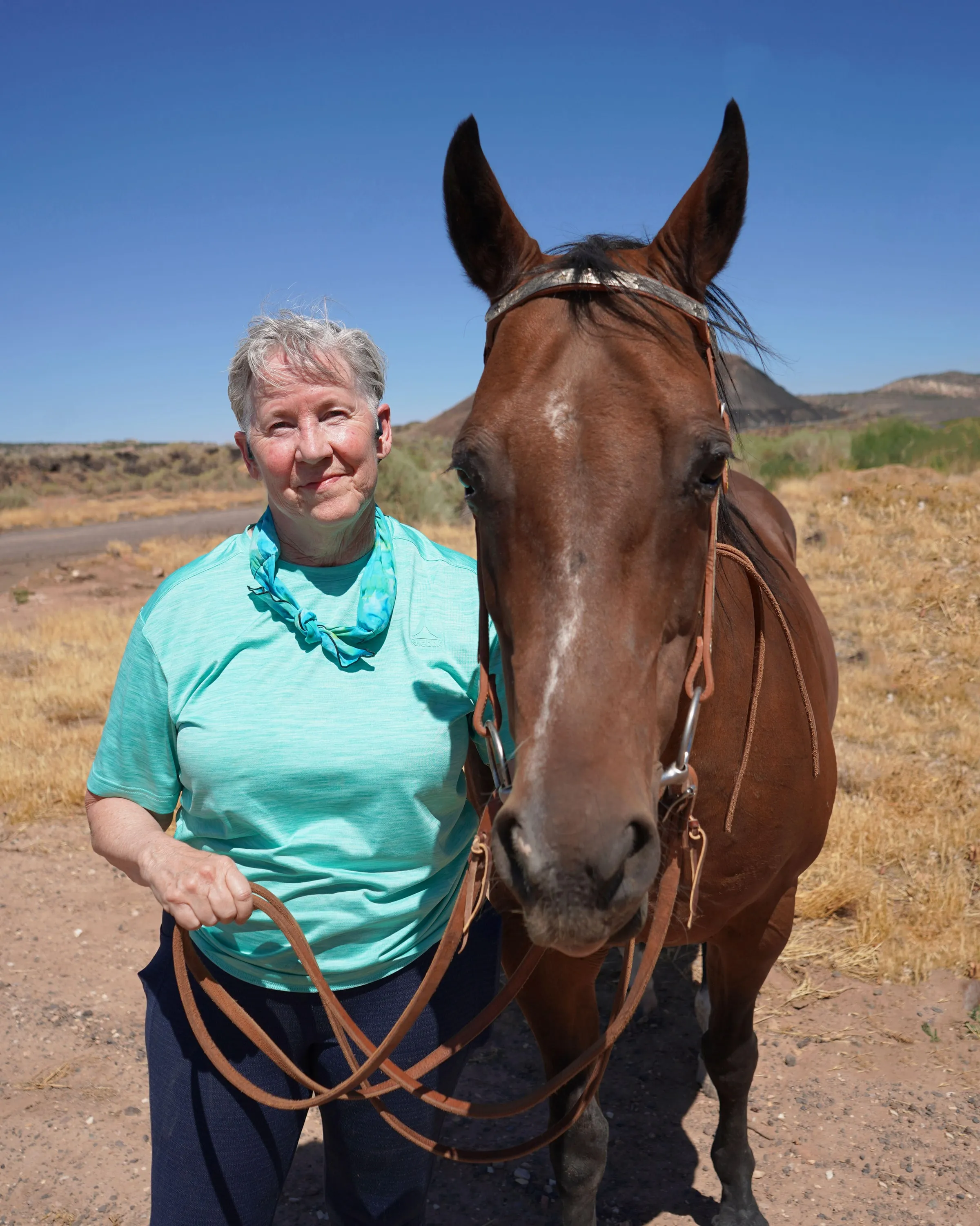 Chris Weeks standing beside a bay horse in red rock country